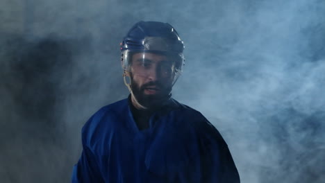 Professional-hockey-player-with-a-stick-and-a-puck-moves-on-Luda-in-skates-and-helmet-on-a-dark-background-and-smoke.-Dribbling-with-the-puck-of-a-young-man-on-the-ice-arena